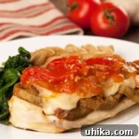 Plate of Chicken Sorrentino - chicken breast topped with eggplant, melted cheese, and tomato sauce, served with sautéed spinach and pasta shells.
