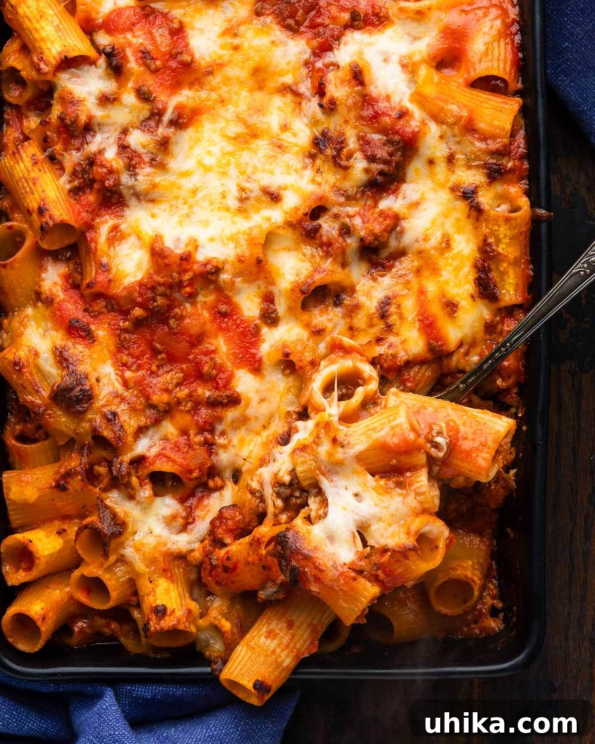 Quick Baked Rigatoni with Savory Meat Ragu 2 Scooping out a portion of pasta al forno, showcasing rich meat sauce, perfectly cooked rigatoni, and melted mozzarella.