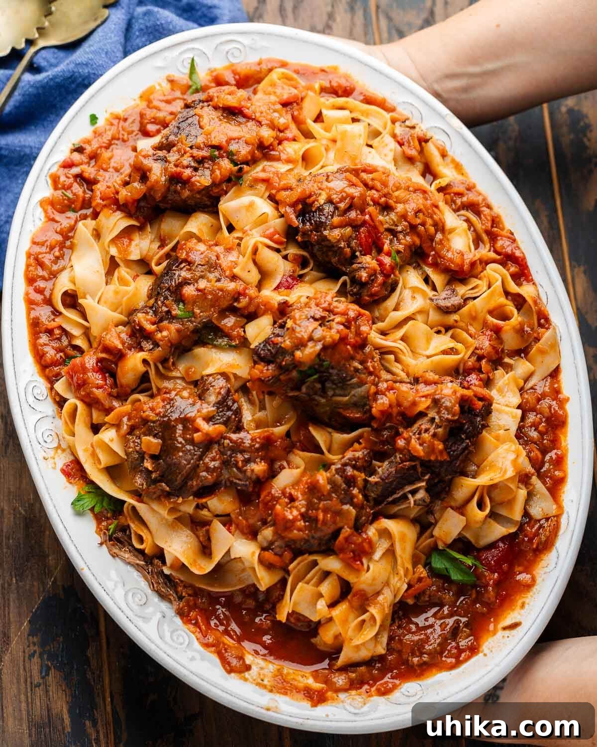 Stracotto Slow-Cooked Italian Pot Roast 2 Hands holding platter of stracotto and pappardelle.