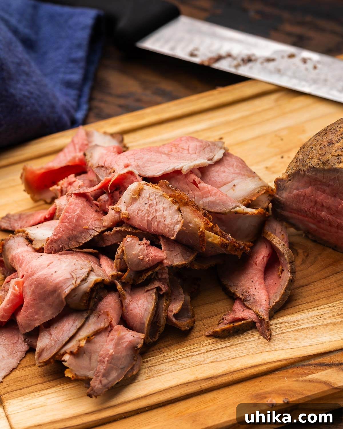 Gourmet Deli Roast Beef 7 Deli roast beef thinly sliced on a wooden cutting board.