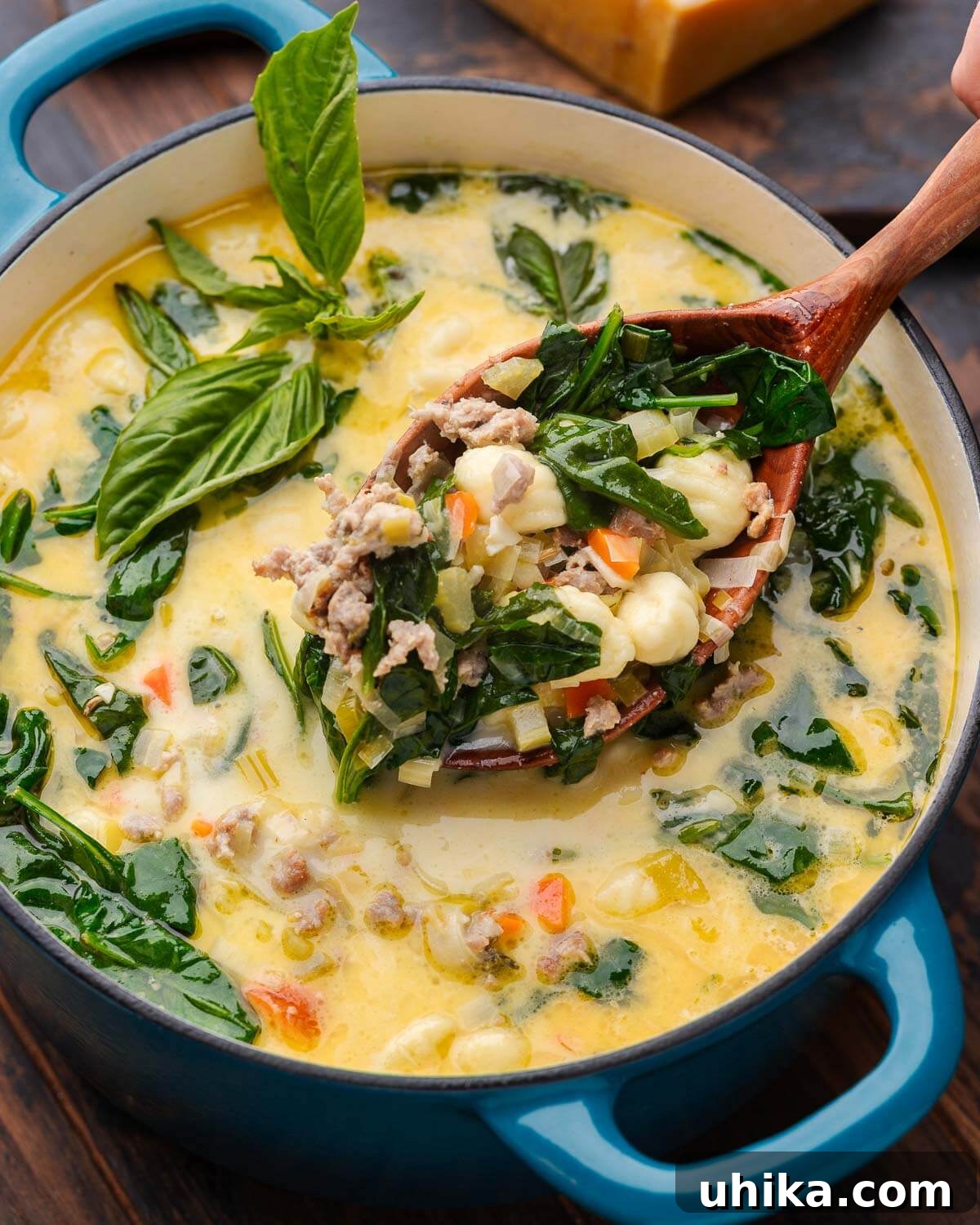Hearty Sausage Gnocchi Soup 7 Large wooden ladle holding big scoop of sausage gnocchi soup over Dutch oven pot.