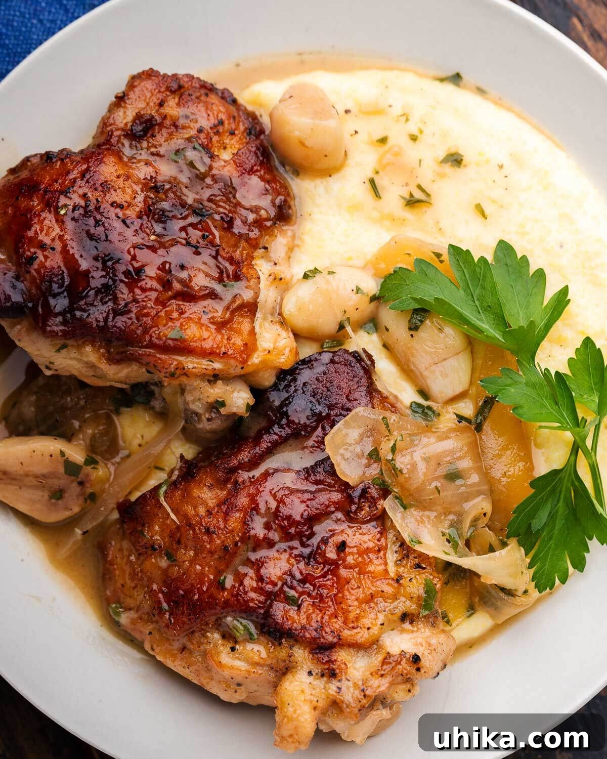 Zesty Italian Vinegar Chicken 7 White plate showcasing two generous pieces of Italian vinegar chicken, perfectly braised, served alongside creamy polenta and garnished with fresh parsley.