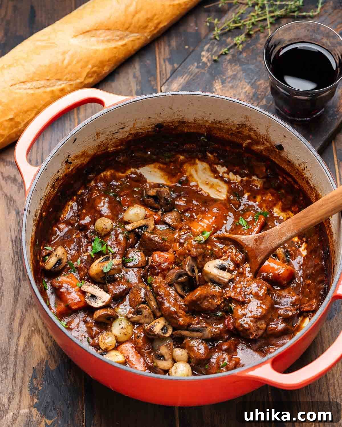 10 Must-Have Kitchen Tools for Your Fall Cooking 2 A perfectly cooked Beef Bourguignon simmering in a vibrant red Dutch oven, accompanied by a crusty baguette and a glass of red wine, embodying the essence of cozy autumn meals.