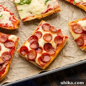 6 slices of French bread pizza on brown parchment paper lined baking sheet.