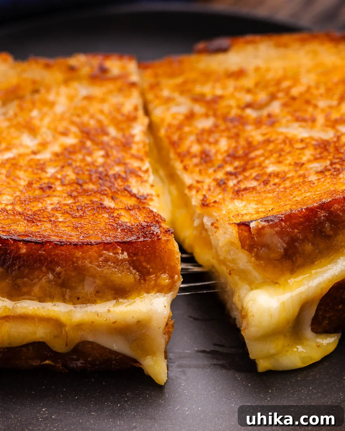 Perfectly Golden Grilled Cheese Indulgence 2 Closeup shot of perfectly golden-brown, sliced sourdough grilled cheese, revealing its gooey, melted interior.