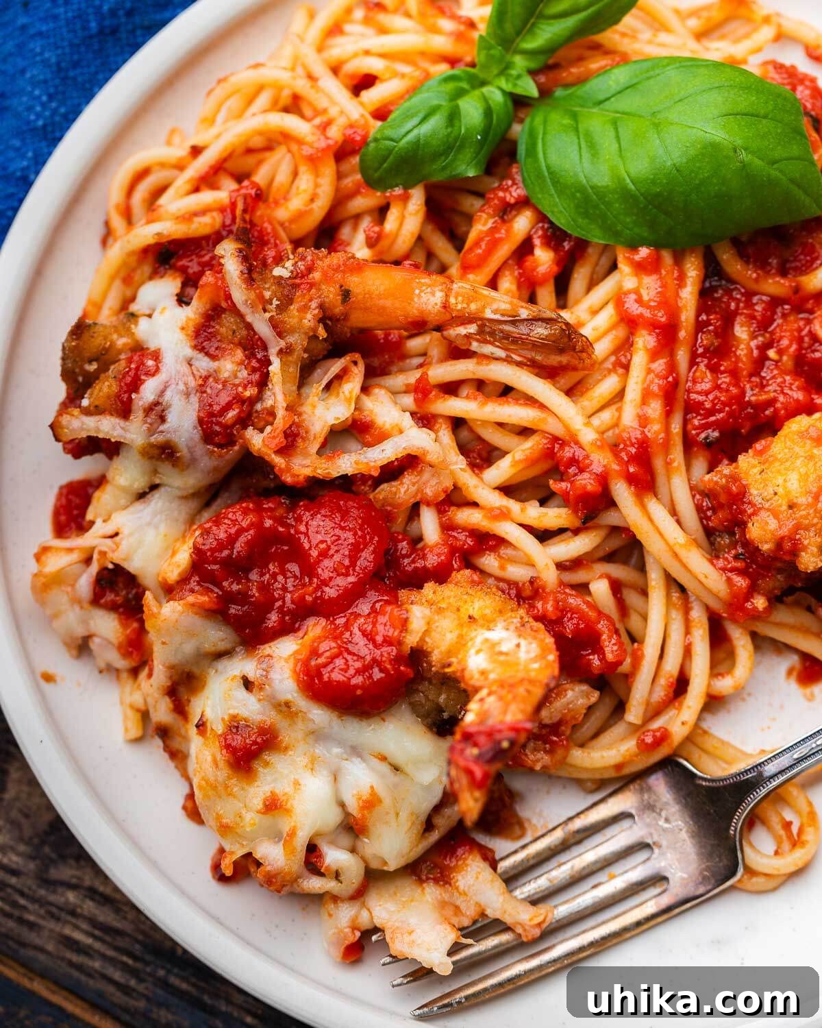 Golden Baked Shrimp Parm 2 White plate with spaghetti and shrimp parmesan.