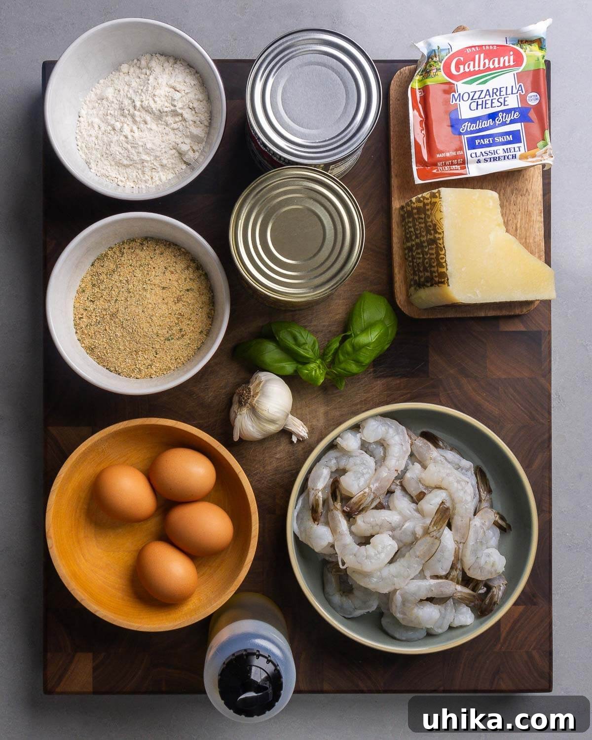 Golden Baked Shrimp Parm 3 Ingredients shown: flour, canned tomatoes, mozzarella, Pecorino Romano, seasoned breadcrumbs, basil, garlic, eggs, shrimp, and olive oil.
