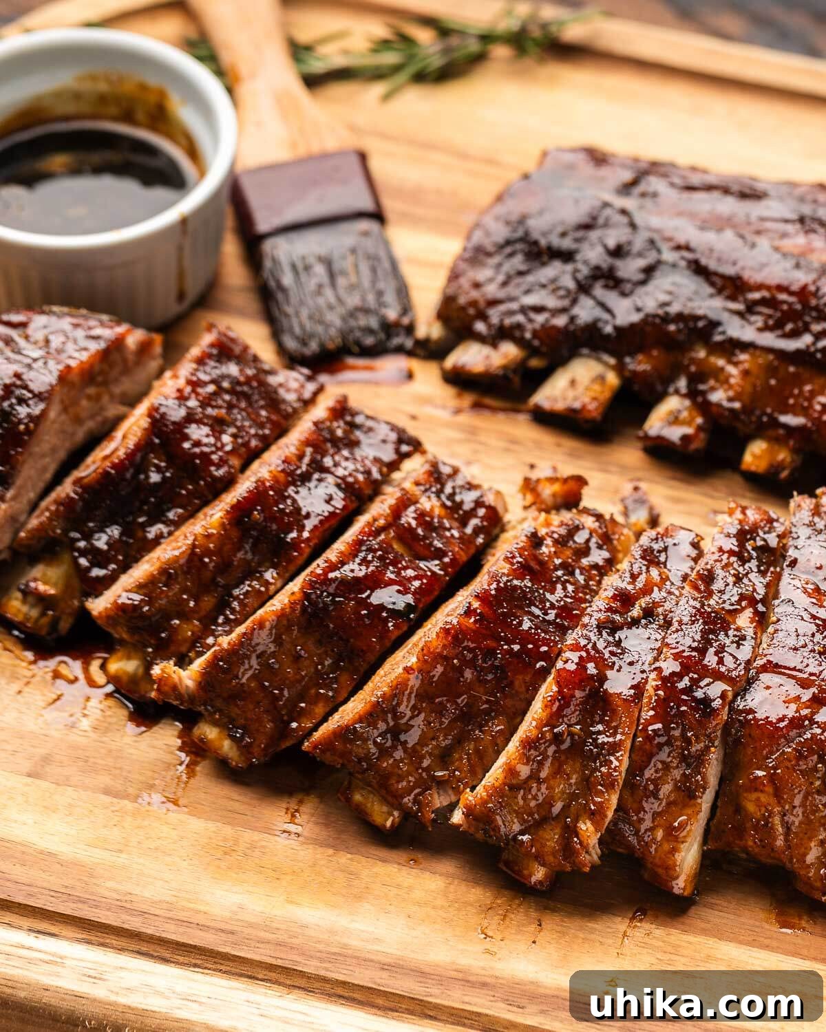 Rustic Tuscan Balsamic Glazed Ribs 6 Sliced ribs on cutting board with small bowl of balsamic glaze and brush.