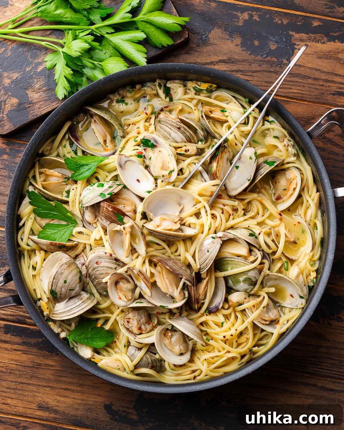 Large pan with linguine alle vongole along with side board of parsley.