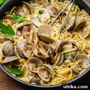 Linguine alle vongole in black pan with numerous open whole clams.