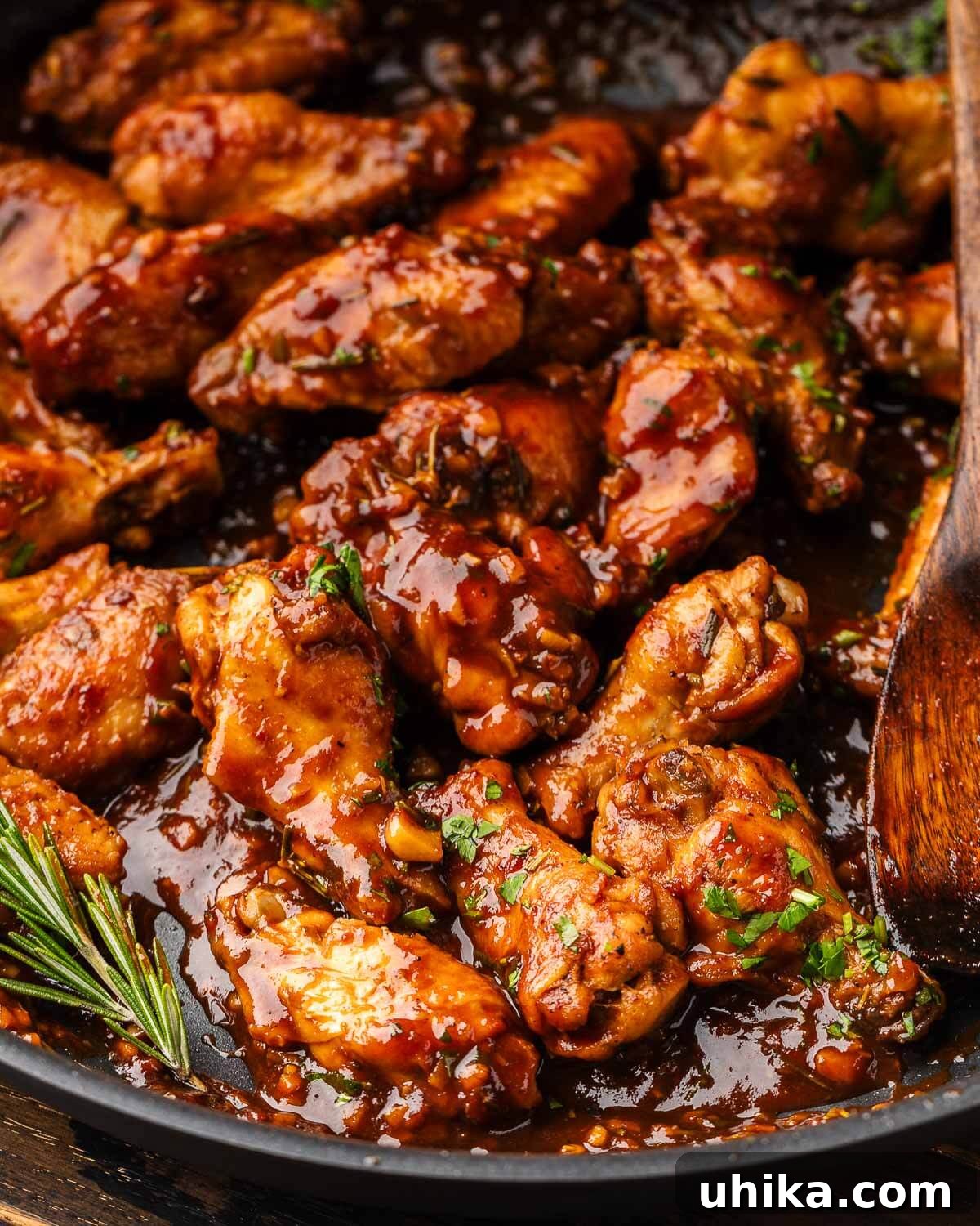 Luscious Balsamic Braised Wings 2 Pan of balsamic braised chicken wings, garnished with fresh rosemary.