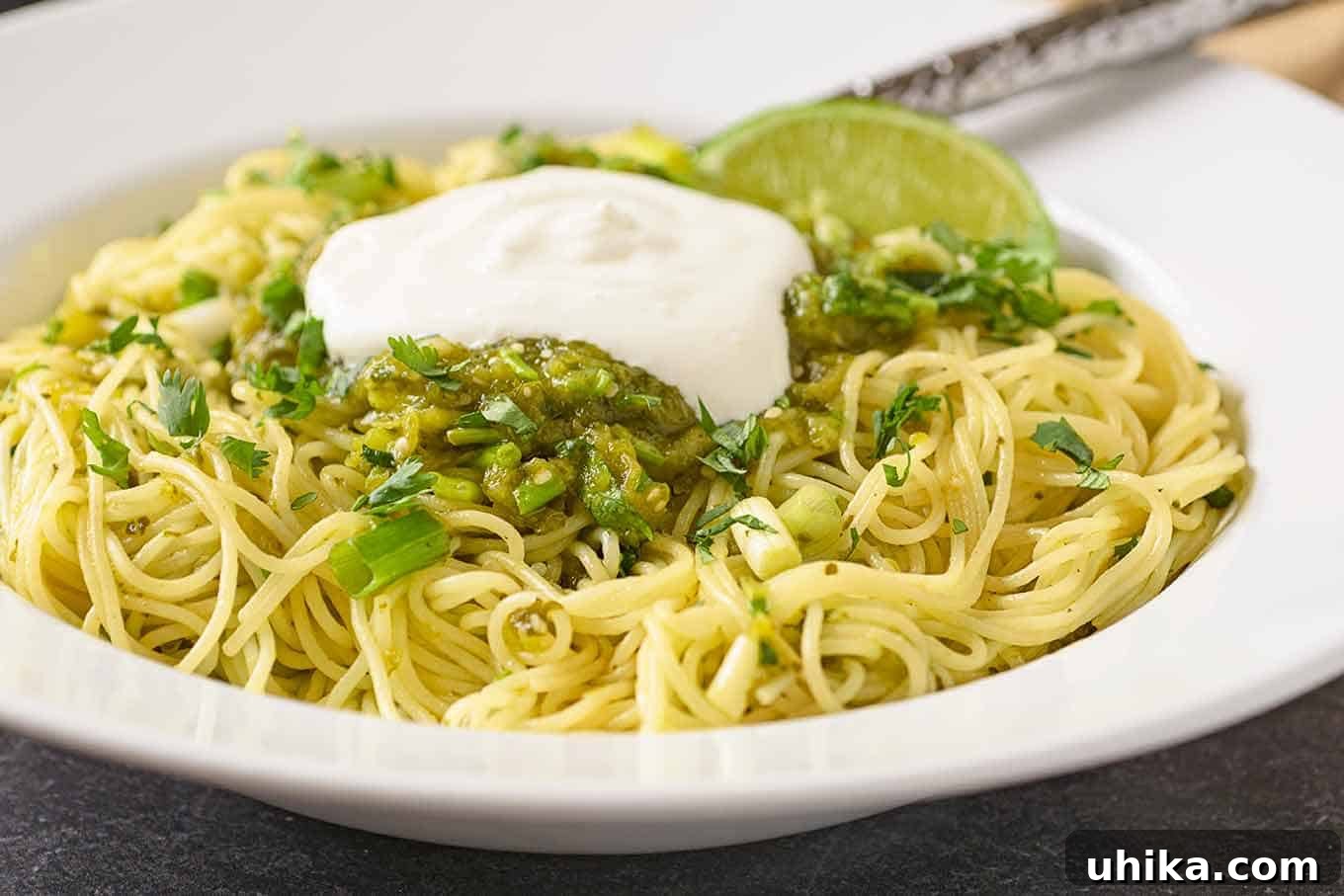 Emerald Pasta 4 A close-up view of spaghetti perfectly tossed with a rich salsa verde made from tomatillos, poblano peppers, fresh lime, scallions, and cilantro, crowned with a generous dollop of sour cream.