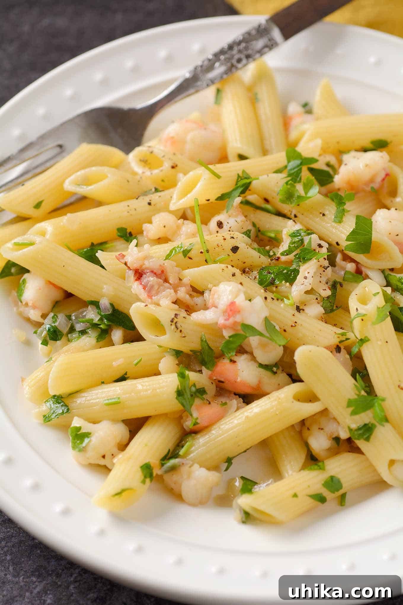 Decadent Lobster Pasta with Truffle Essence 3 A close-up view showcasing the rich texture of lobster pasta, featuring penne coated in a creamy white wine butter sauce, adorned with tender lobster chunks, finely chopped shallots, and fresh parsley.