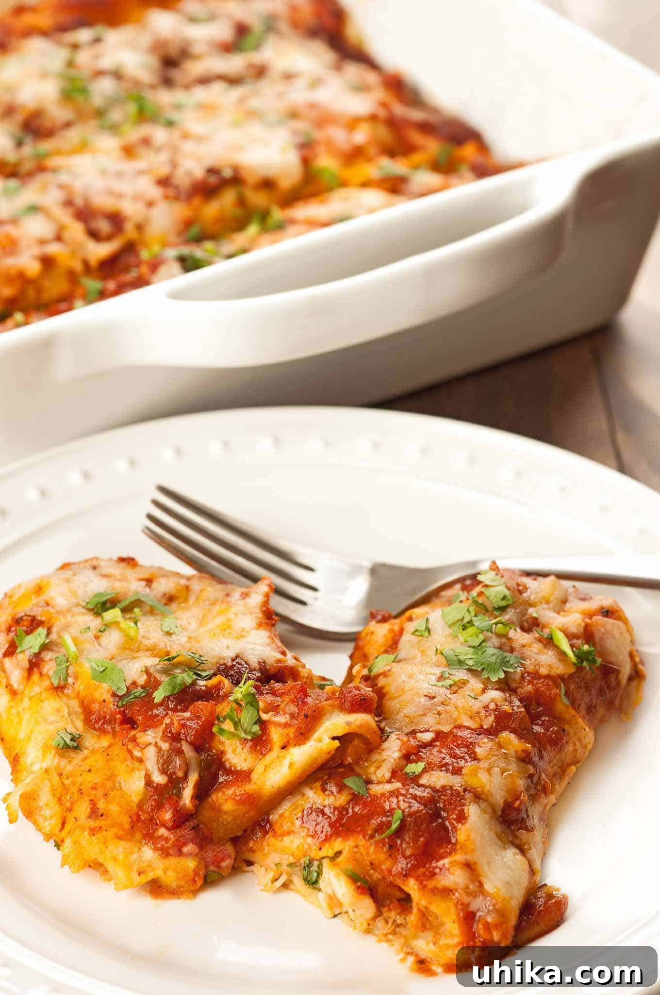 Smothered Chicken Enchilada Bake 2 A vibrant plate of classic homemade chicken enchiladas, generously smothered in a rich, zesty red sauce, topped with melted cheese and fresh cilantro. In the background, a full casserole dish promises more delicious servings.