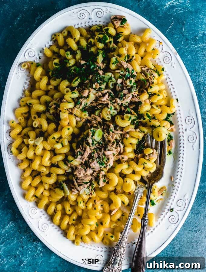 Tuna pasta served in a large white serving platter, garnished with fresh parsley.