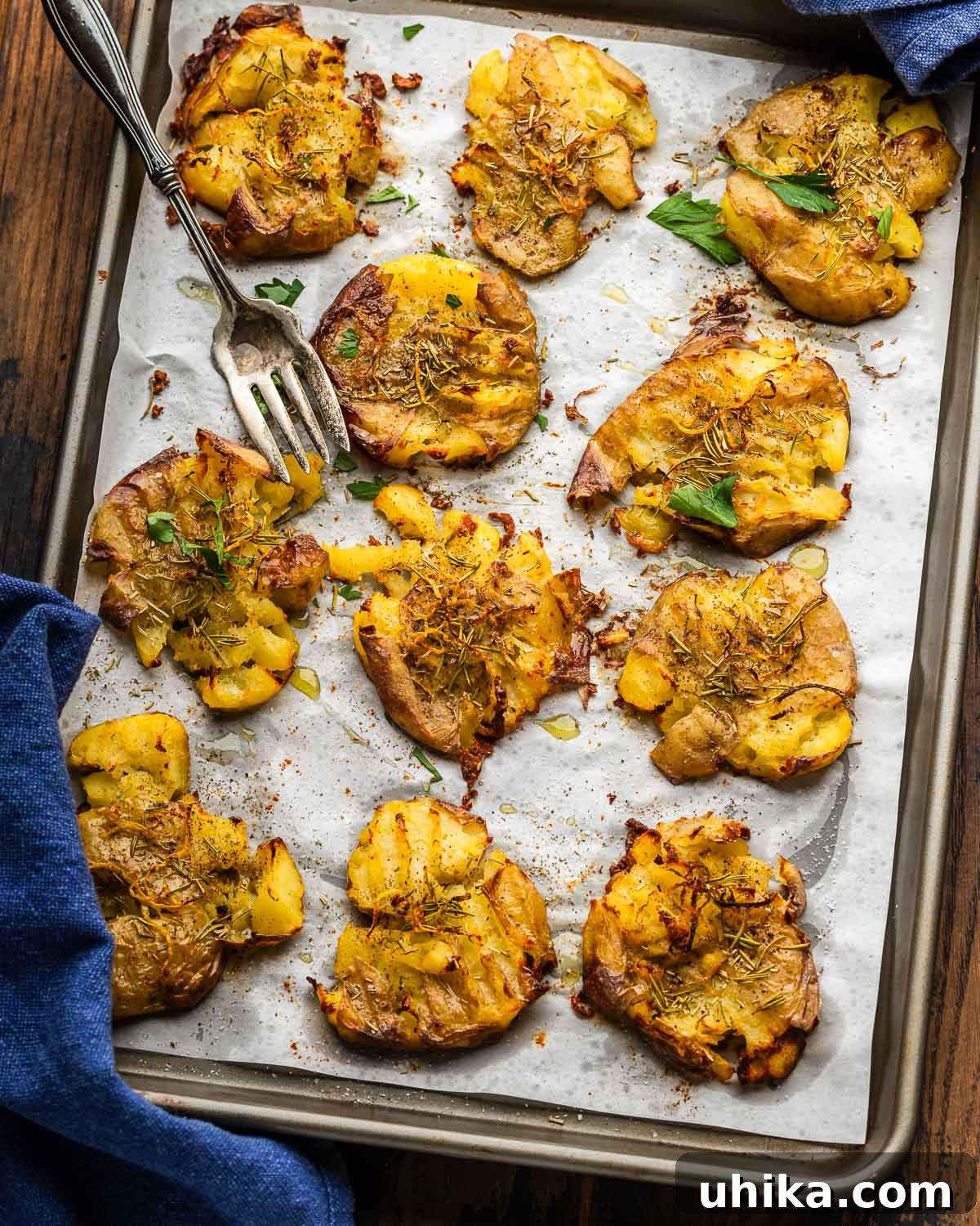 Crispy Rosemary Lemon Smashed Potatoes 2 Baking sheet with golden brown, perfectly crispy rosemary lemon smashed potatoes and a large serving fork.
