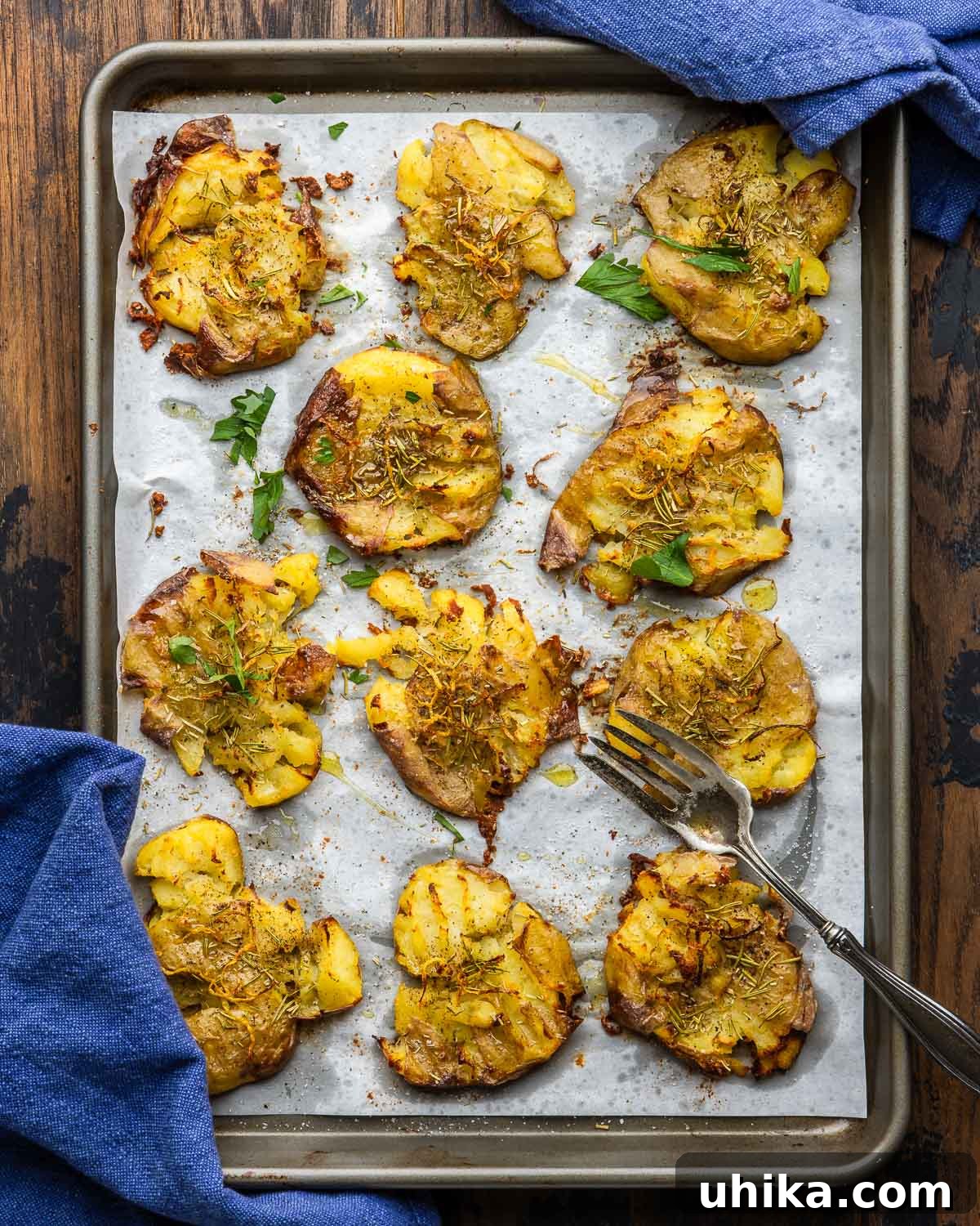 Crispy Rosemary Lemon Smashed Potatoes 5 A close-up shot of a large baking sheet filled with golden brown, perfectly crispy smashed potatoes, garnished with fresh herbs and ready to be served.