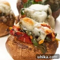 Close-up photo of spinach stuffed mushrooms with melted cheese on top, served on a white plate.