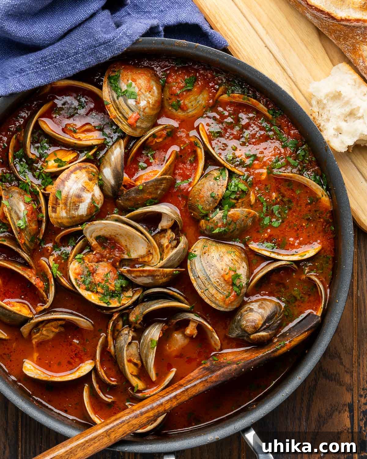 Seafood Spectacle: Recipes for Your Seven Fish Feast 13 Clams in a vibrant red sauce, served in a large pan with crusty bread on the side for dipping.