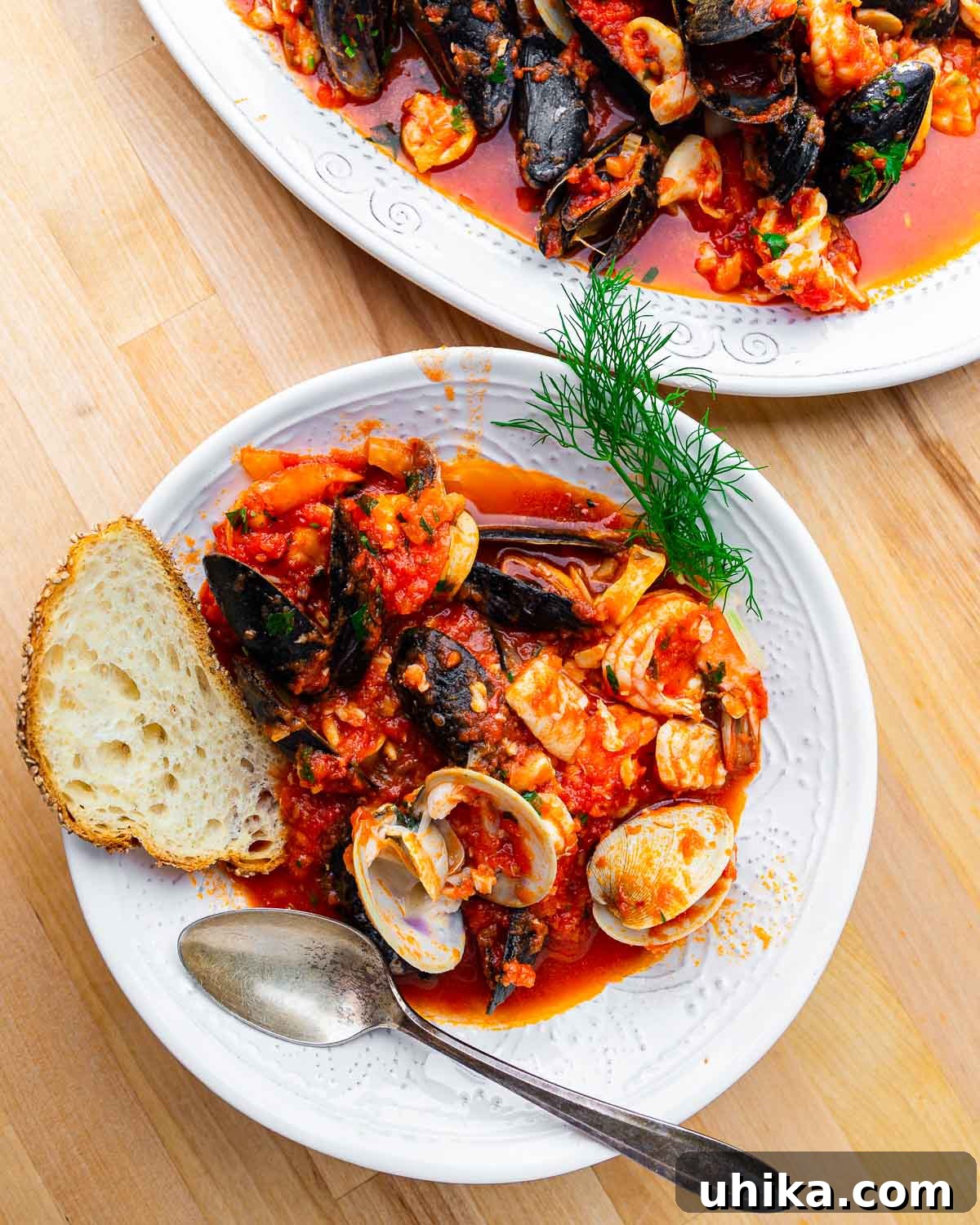 Seafood Spectacle: Recipes for Your Seven Fish Feast 3 Overhead shot of a white bowl filled with Zuppa di Pesce, featuring clams, mussels, shrimp, and toasted bread for dipping.
