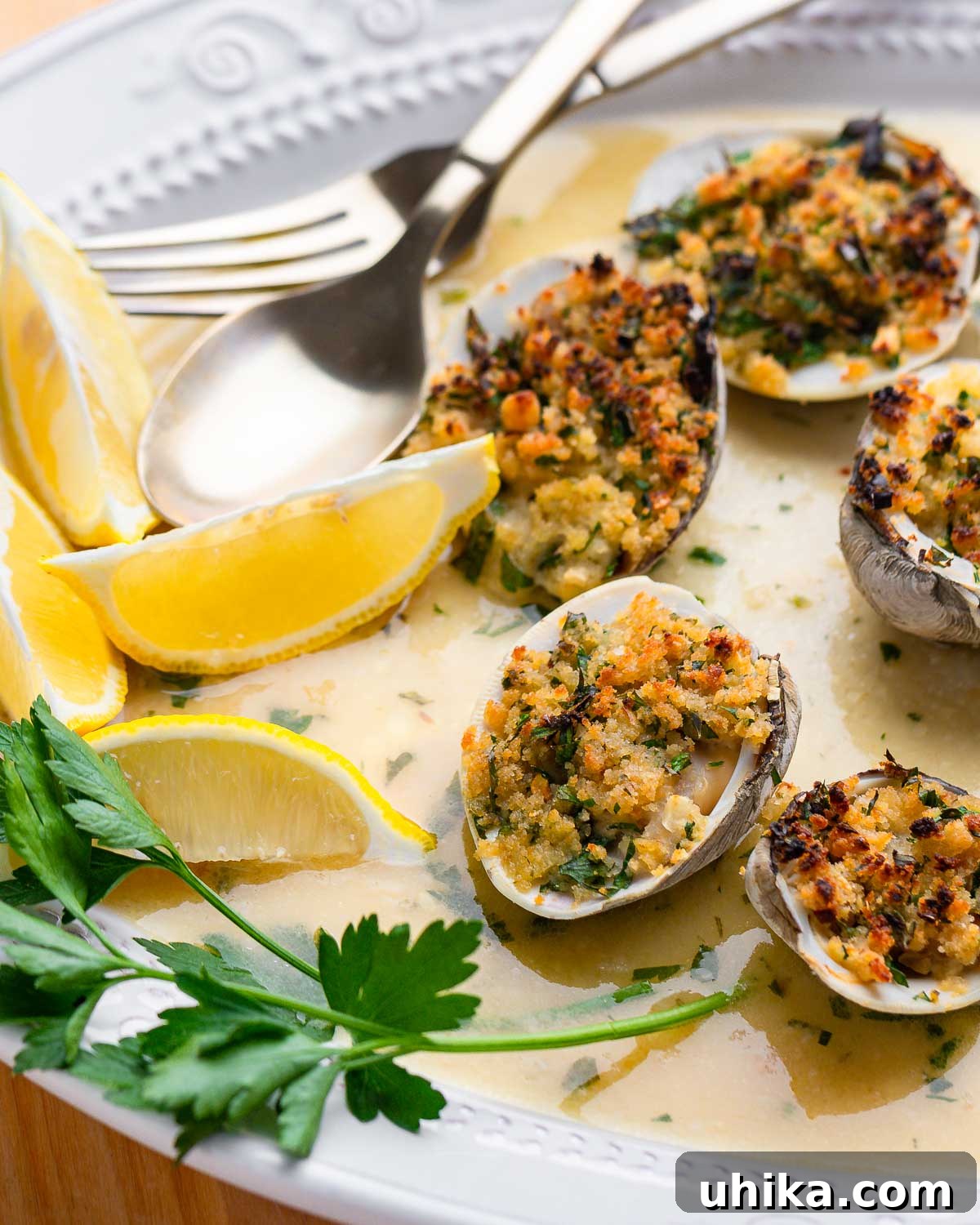 Seafood Spectacle: Recipes for Your Seven Fish Feast 7 Clams Oreganata beautifully arranged in a white dish, garnished with fresh parsley and lemon wedges.