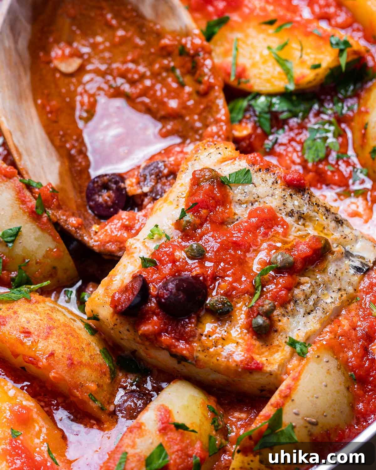 Seafood Spectacle: Recipes for Your Seven Fish Feast 9 Piece of Baccala (salt cod) simmering in a rich tomato sauce, with a large wooden spoon nearby.