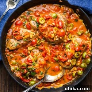 Overhead shot of large black pan with Sicilian-style tuna steaks covered in olive tomato sauce.
