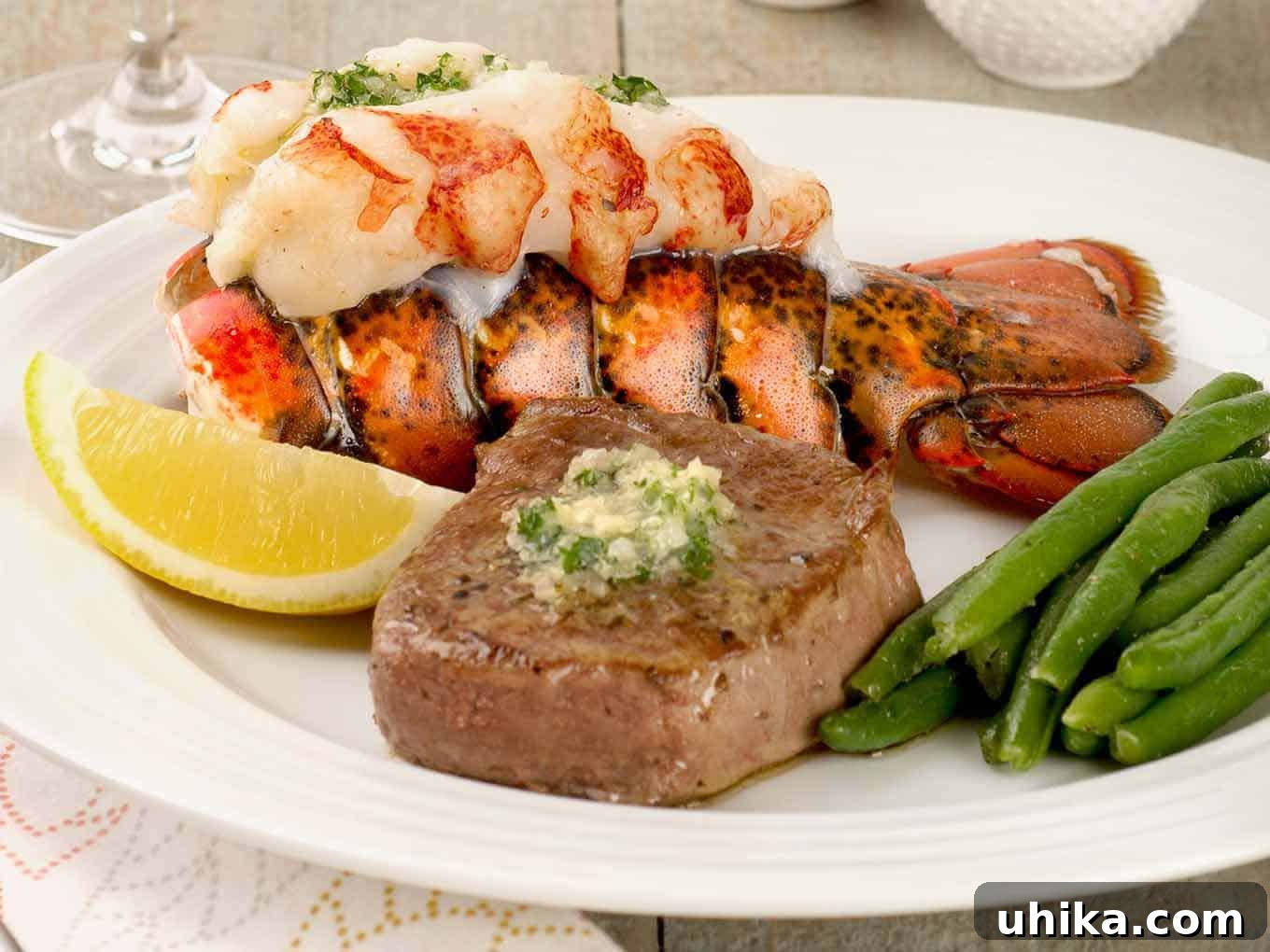Lobster and Steak Grandeur 3 A beautifully plated surf and turf dinner featuring a perfectly pan-seared filet mignon, a succulent lobster tail adorned with compound butter, crisp green beans, and a fresh lemon wedge garnish. This easy recipe makes gourmet dining at home simple.