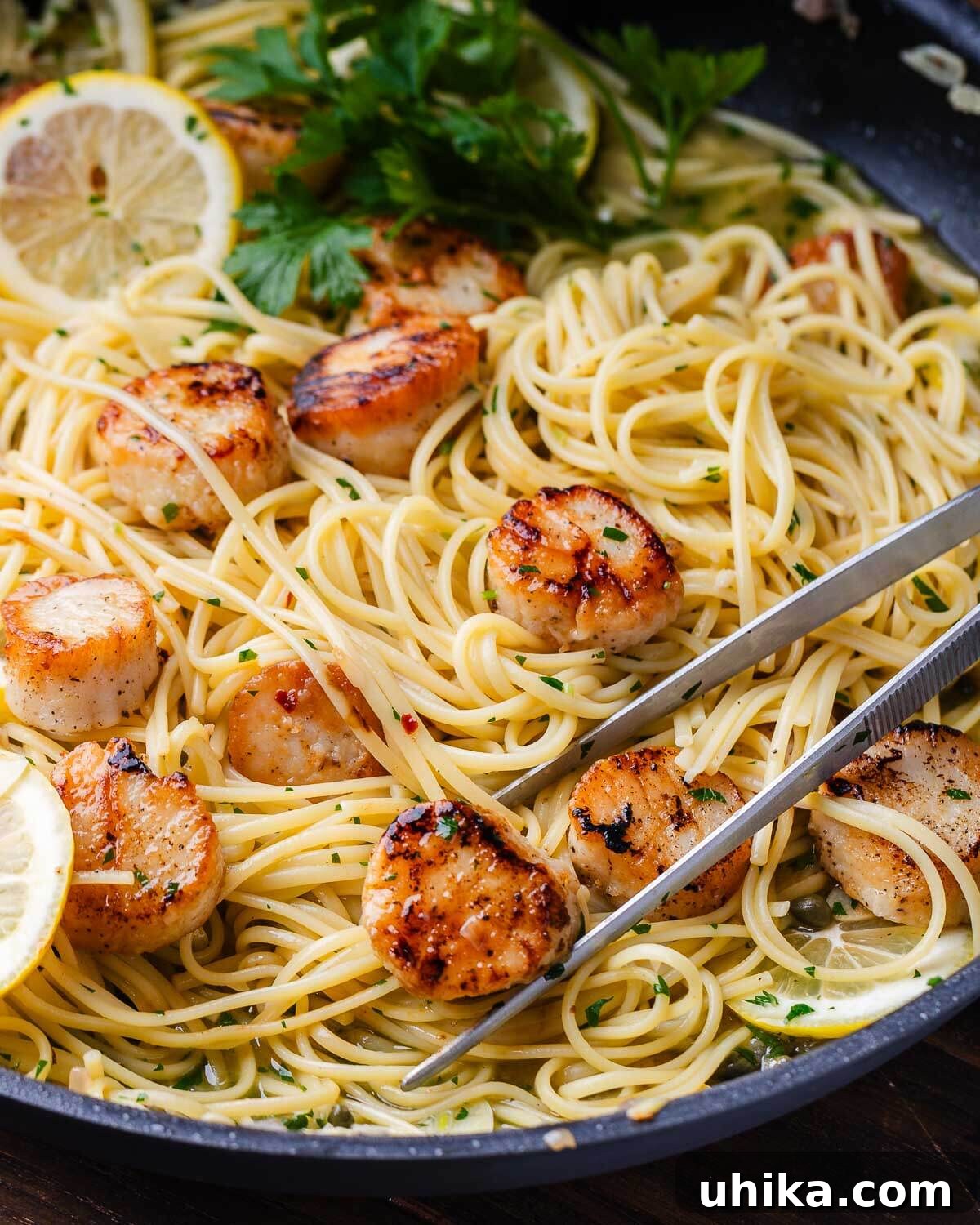 Pan Seared Scallops with Lemon Garlic Pasta 2 Tweezers holding seared scallop over linguine.