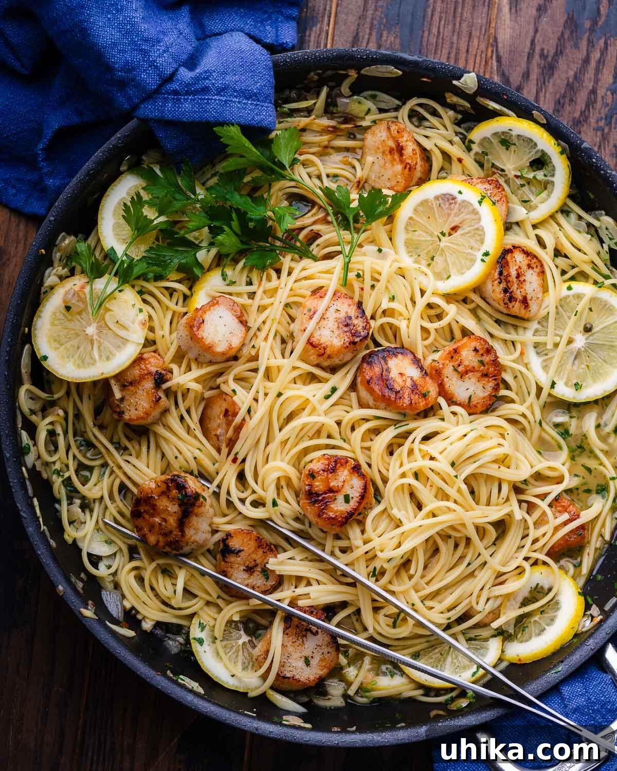Pan Seared Scallops with Lemon Garlic Pasta 6 Lemon garlic scallop pasta in black pan with 2 blue napkins.