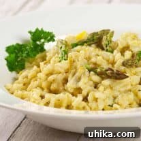 Creamy asparagus and lemon risotto garnished with parsley and asparagus tips, served in a white bowl.