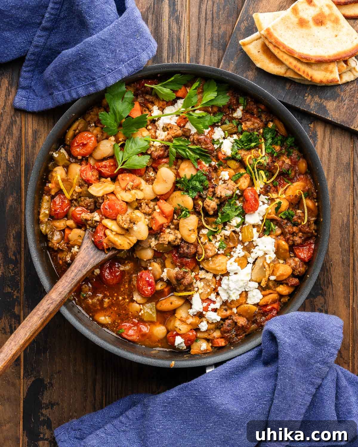 Hearty Greek Sausage and Bean Stew 6 Large pan with Greek beans and sausage (Fassolada me Loukaniko) with pita on the side, ready to be enjoyed.