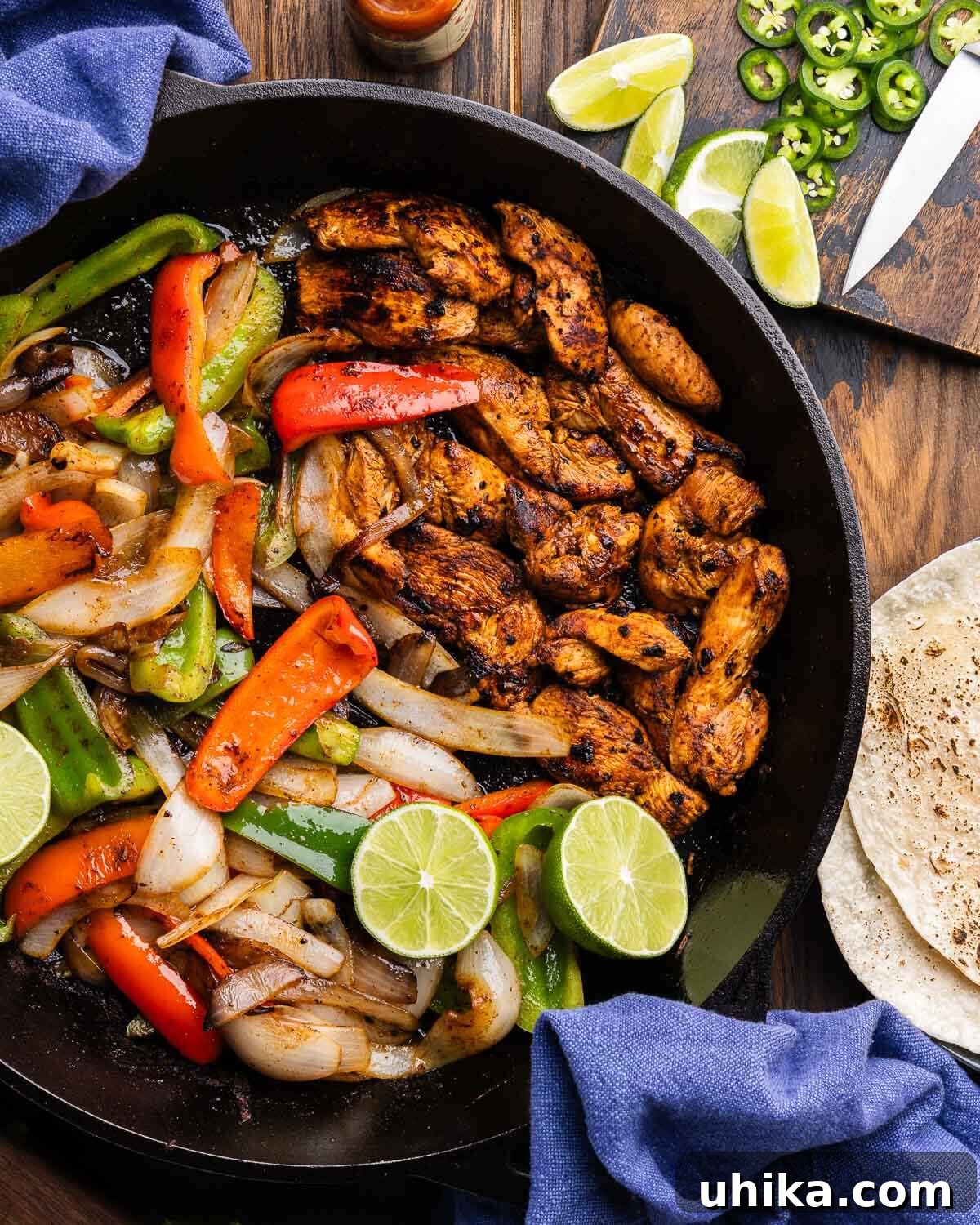 Sizzling Chicken Fajita Fiesta 2 Large cast iron pan with chicken fajitas surrounded by side of jalapenos, limes, and tortillas.