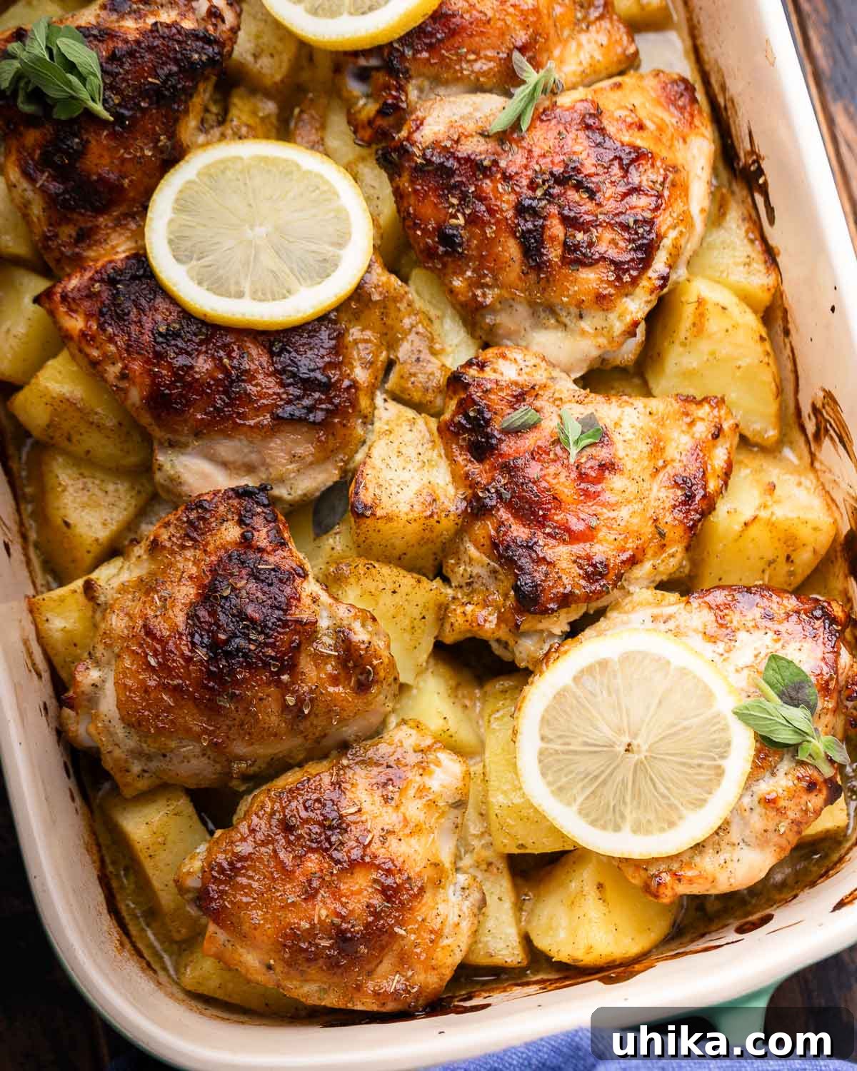 Bright Greek Lemon Chicken and Crispy Potatoes 2 Greek lemon chicken and potatoes in baking dish with sliced lemons on top, garnished with fresh herbs. A perfectly roasted one-pan meal.