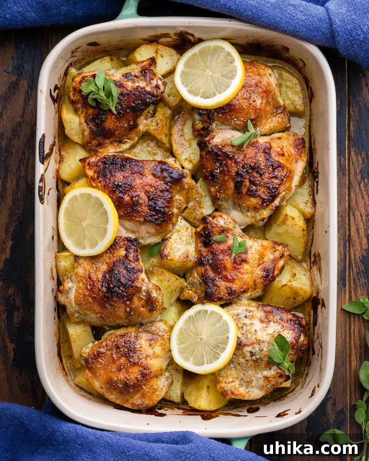 Bright Greek Lemon Chicken and Crispy Potatoes 6 Plated Greek lemon chicken and potatoes on a wooden table with blue napkins, ready to serve.