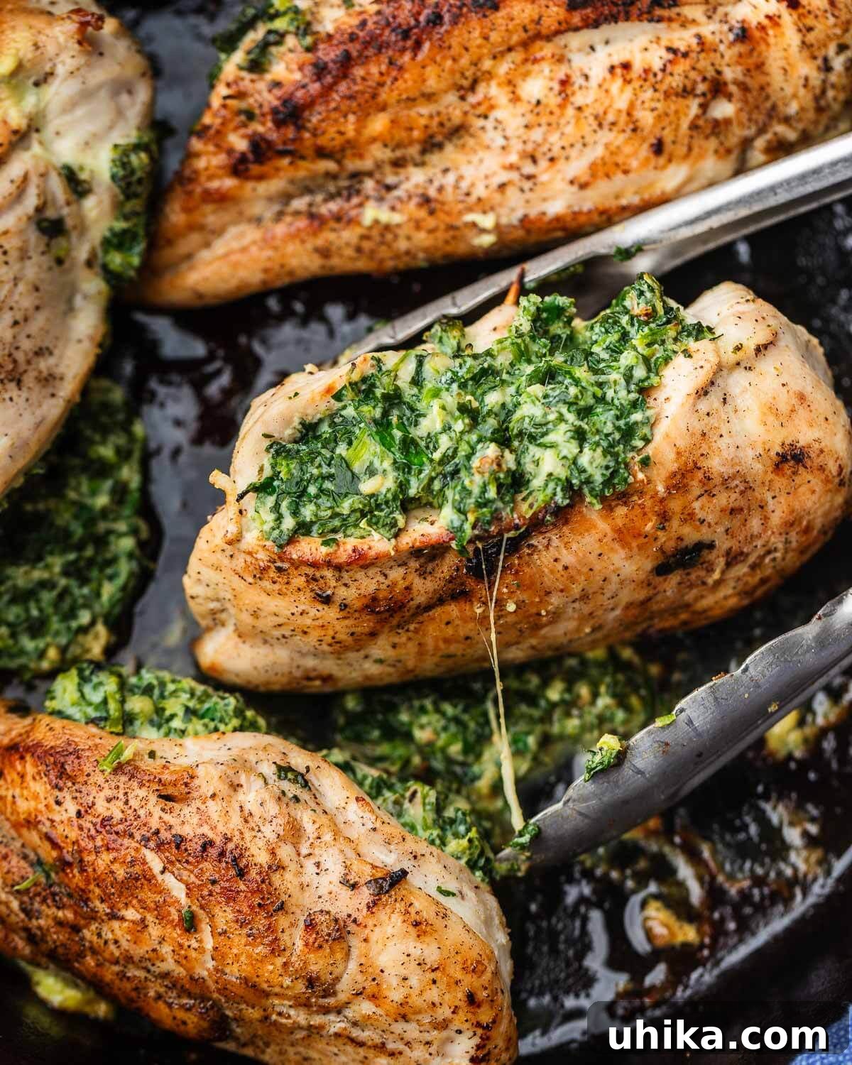 Effortless Spinach Stuffed Chicken 6 Tongs holding a perfectly cooked spinach and cheese stuffed chicken breast, showing the golden exterior and peeking filling.