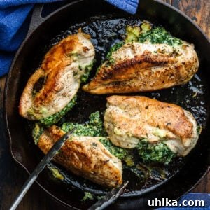 Four Spinach stuffed chicken breasts in cast iron pan.