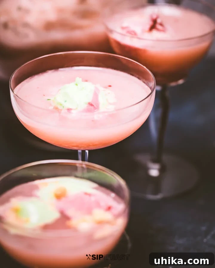 Fizzy Sherbet Delight 2 Glasses of vibrant sherbet punch, garnished with frozen fruit and a scoop of sherbet, ready to serve.