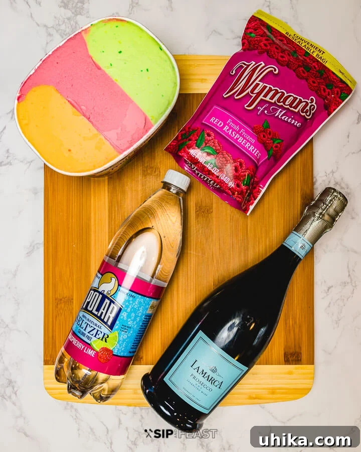 Fizzy Sherbet Delight 3 Key ingredients for Sherbet Punch: rainbow sherbet, frozen raspberries, a bottle of seltzer, and sparkling prosecco, arranged on a countertop.
