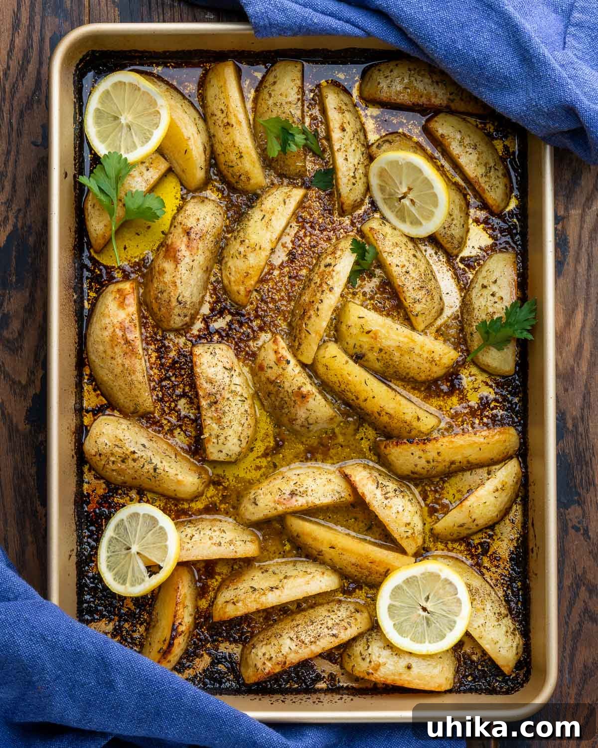 Zesty Lemon Oregano Roasted Greek Potatoes 2 Greek potatoes in large baking pan, garnished with fresh lemon wedges and parsley.
