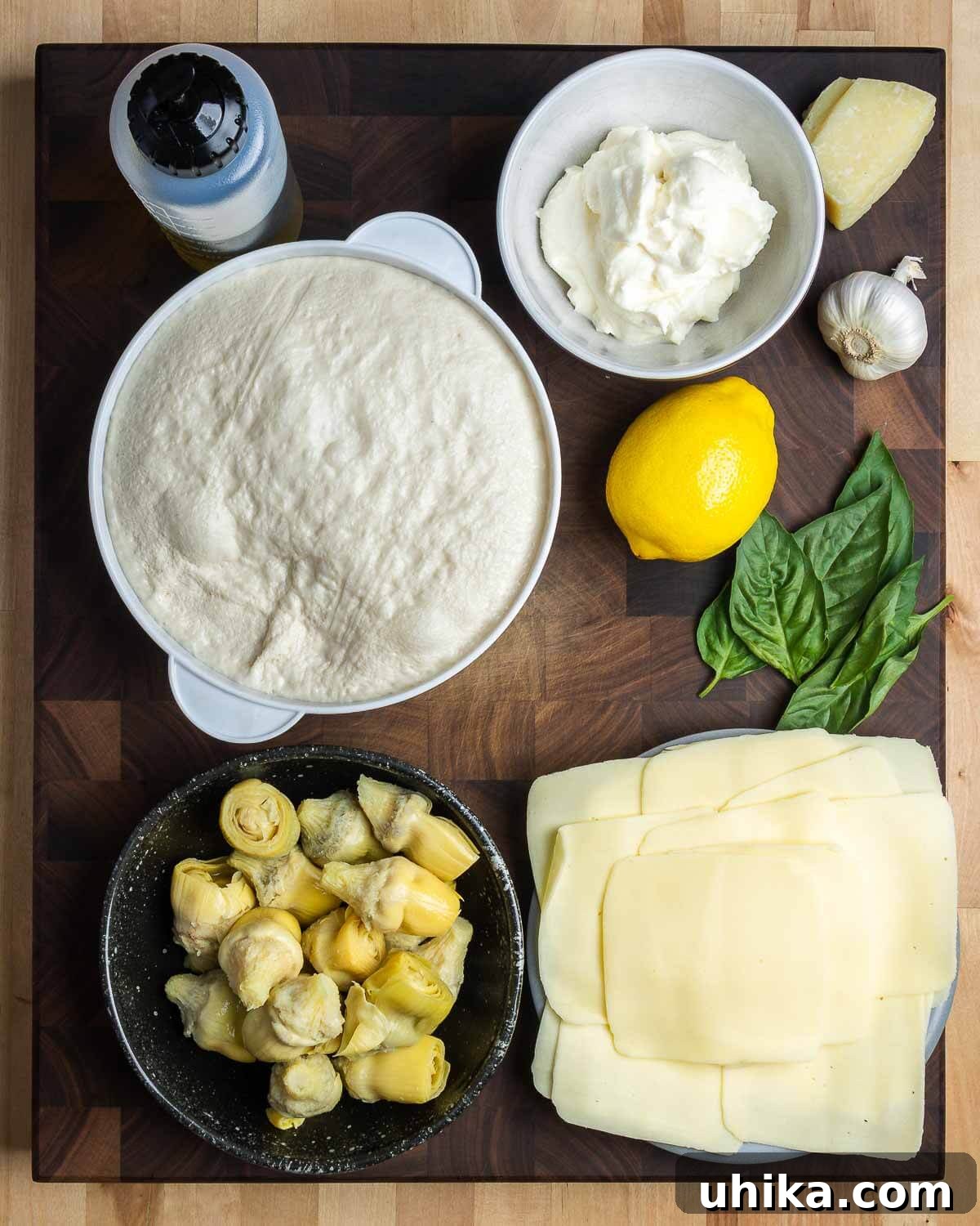 Mediterranean Artichoke Pizza 3 All ingredients for artichoke pizza recipe including olive oil, pizza dough, ricotta, lemon, Pecorino, garlic, basil, artichoke hearts, and sliced mozzarella.