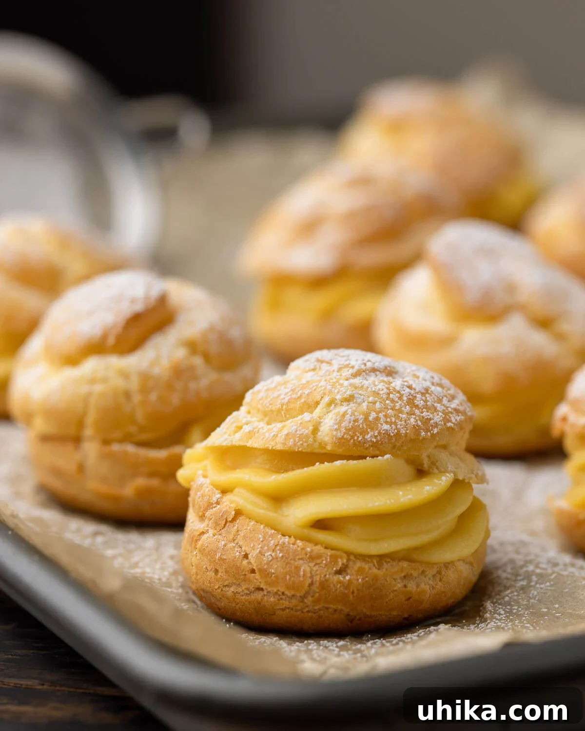 Golden Choux Perfection 2 Cream Puffs with powdered sugar on baking sheet, ready to be served.
