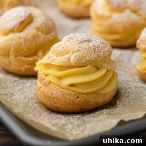 Cream Puffs with powdered sugar on baking sheet.
