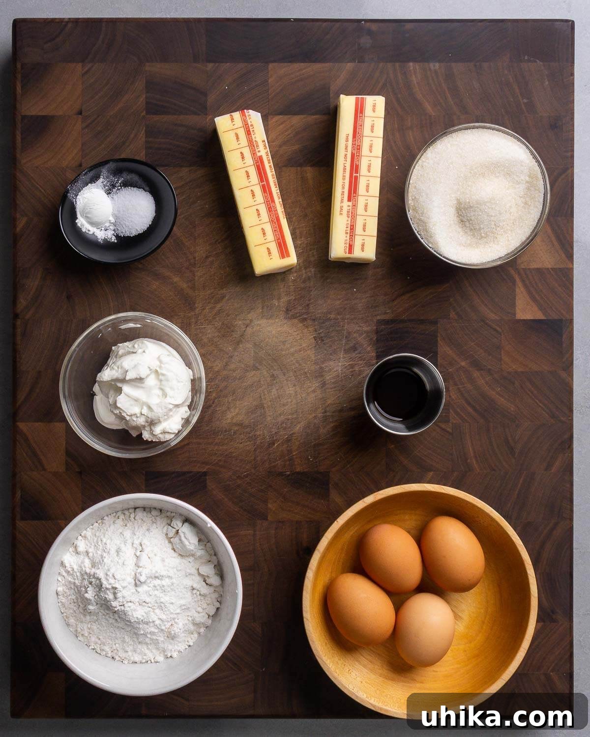 Pound Cake Perfection 4 Ingredients for pound cake laid out: baking powder, salt, butter, sugar, sour cream, vanilla extract, flour, and eggs.