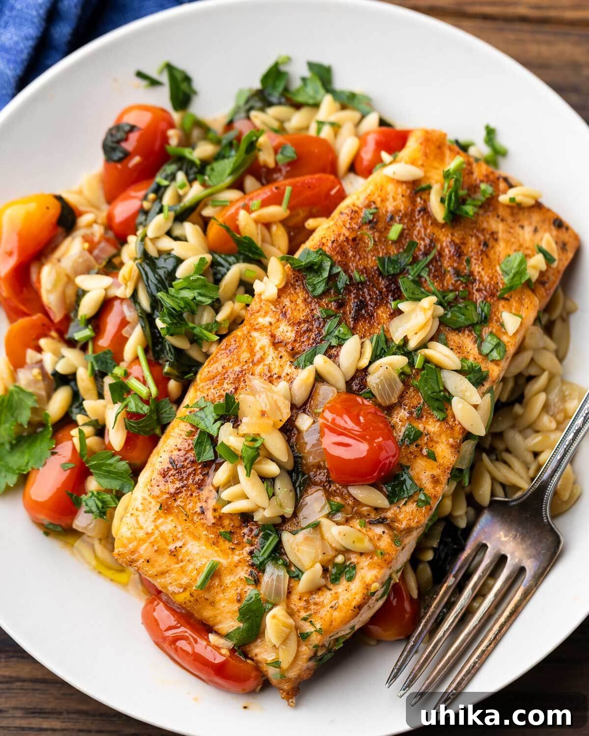 A beautifully plated One-Pan Salmon and Orzo with spinach and cherry tomatoes, ready to be enjoyed.