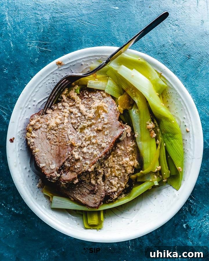 Maiale Al Latte - sipandfeast.com #maialeallatte #dinner #italianrecipe Maiale al latte, milk-braised pork, served with leeks in an elegant small bowl, highlighting the creamy sauce and tender meat.