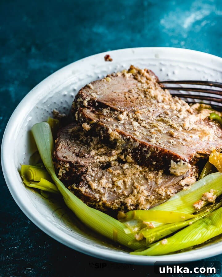 Maiale Al Latte - sipandfeast.com #maialeallatte #dinner #italianrecipe Plated Maiale al latte, featuring generous slices of milk-braised pork shoulder and tender leeks, all glistening with the rich, reduced milk sauce, ready to be enjoyed.
