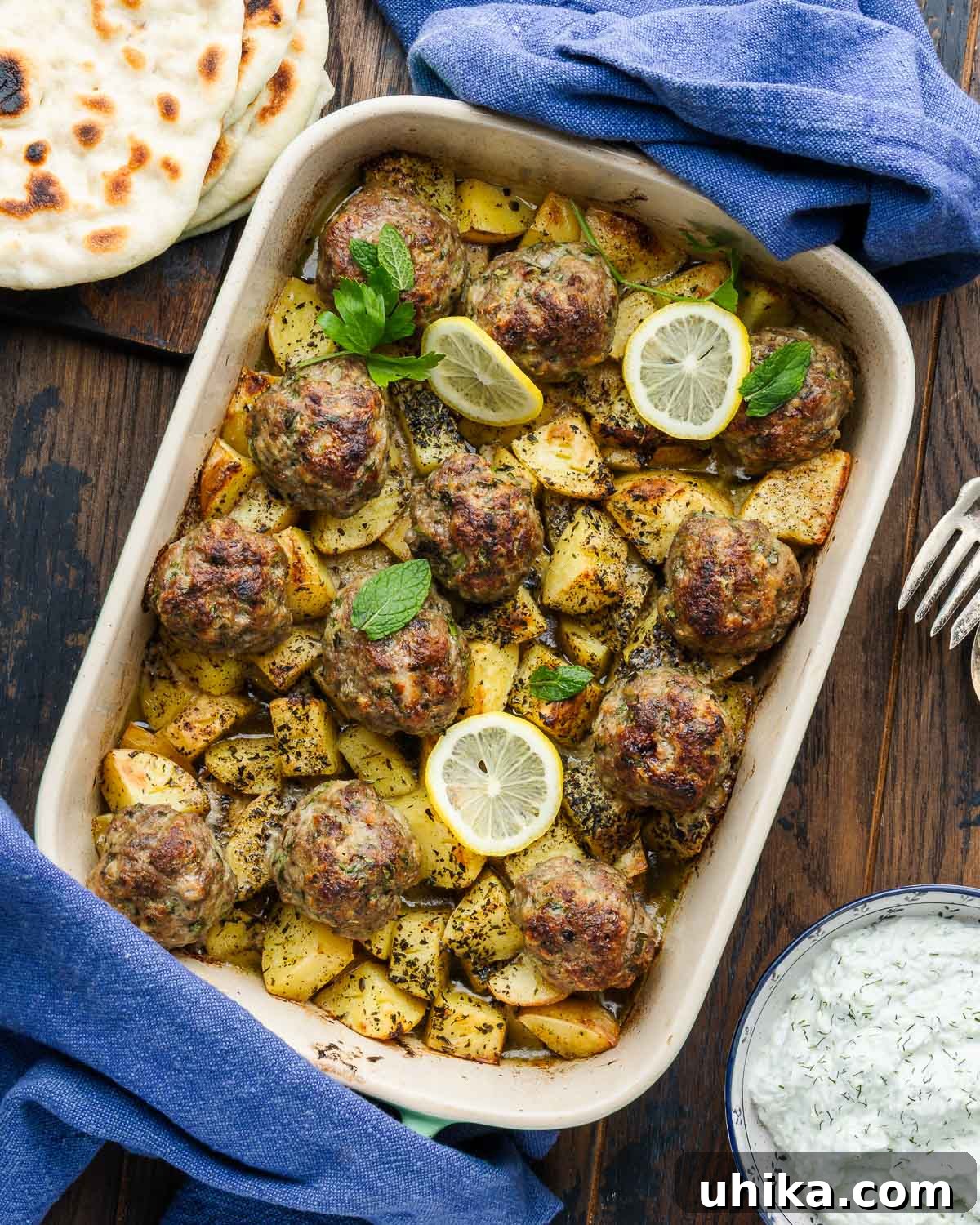 Mediterranean Sheet Pan Meatballs with Roasted Potatoes 2 Flavorful one-pan Greek meatballs and potatoes in a baking dish, served with warm pita bread and creamy tzatziki sauce on the side.