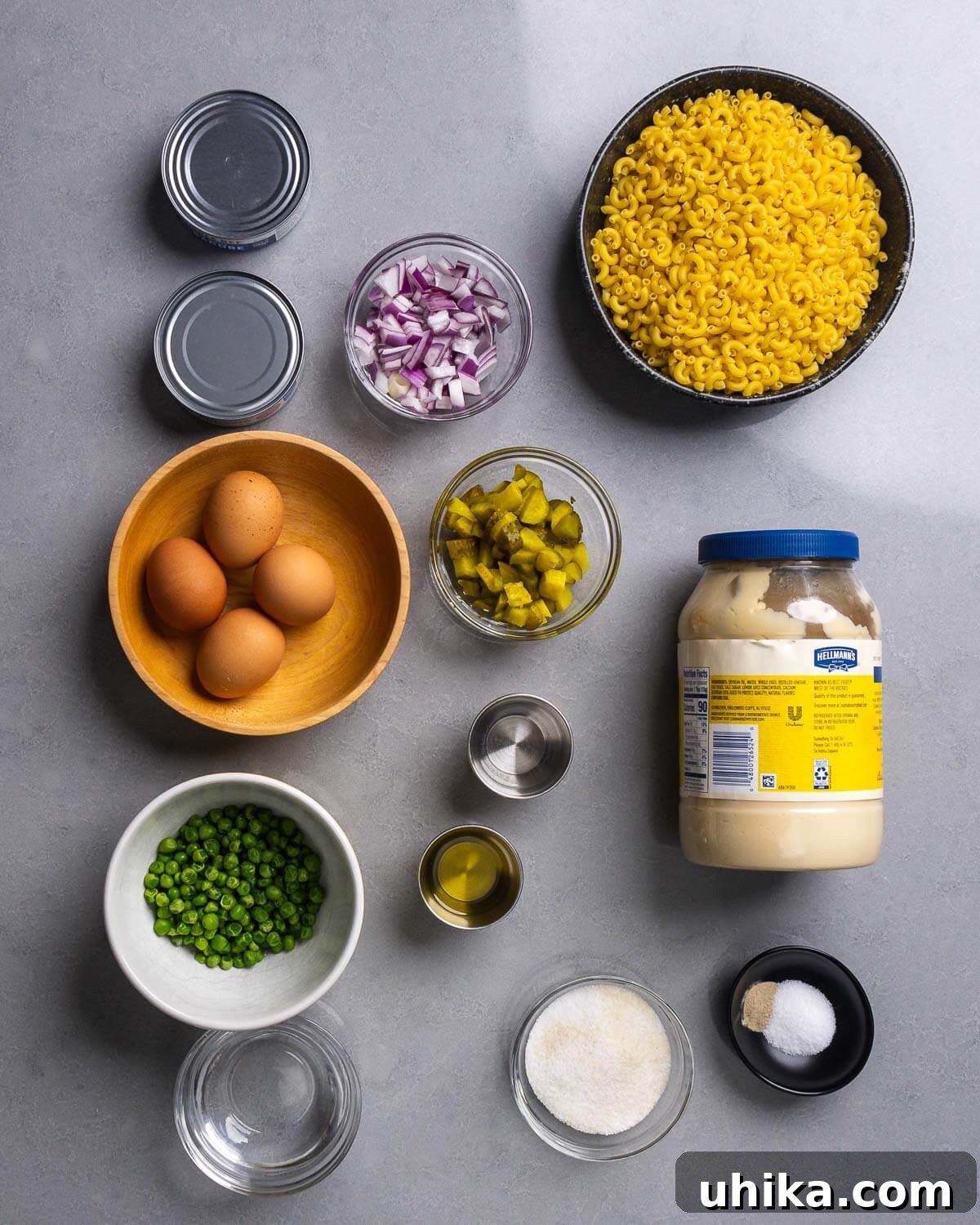 Creamy Tuna Macaroni Sensation 4 A vibrant ingredient collage showcasing all components for the tuna macaroni salad: canned tuna, diced red onion, elbow macaroni, hard-boiled eggs, chopped dill pickles, frozen peas, neutral oil, white vinegar, creamy mayonnaise, water, sugar, fine sea salt, and white pepper.