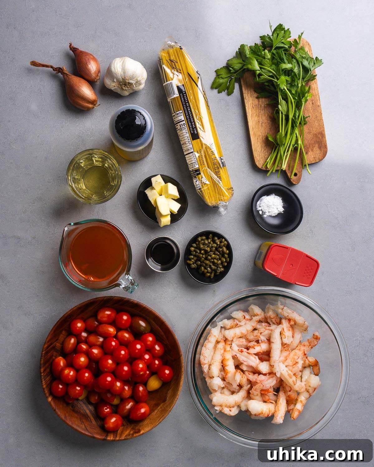Effortless Old Bay Shrimp Capellini for Summer 4 Ingredients for Old Bay Shrimp Capellini, including fresh shallots, garlic cloves, capellini pasta, fresh parsley, dry white wine, unsalted butter, seafood stock, Worcestershire sauce, capers, baking soda, Old Bay seasoning, halved cherry tomatoes, and raw, cleaned shrimp.